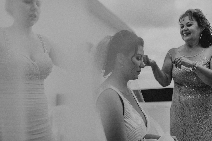 black & white picture of bride putting a veil on