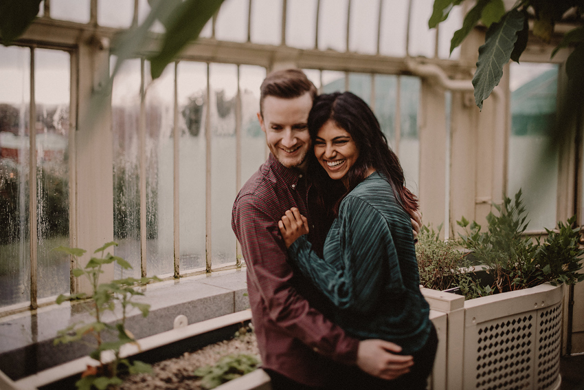 couple laughing and cuddling to each other inside the glasshouse at botanical gardens