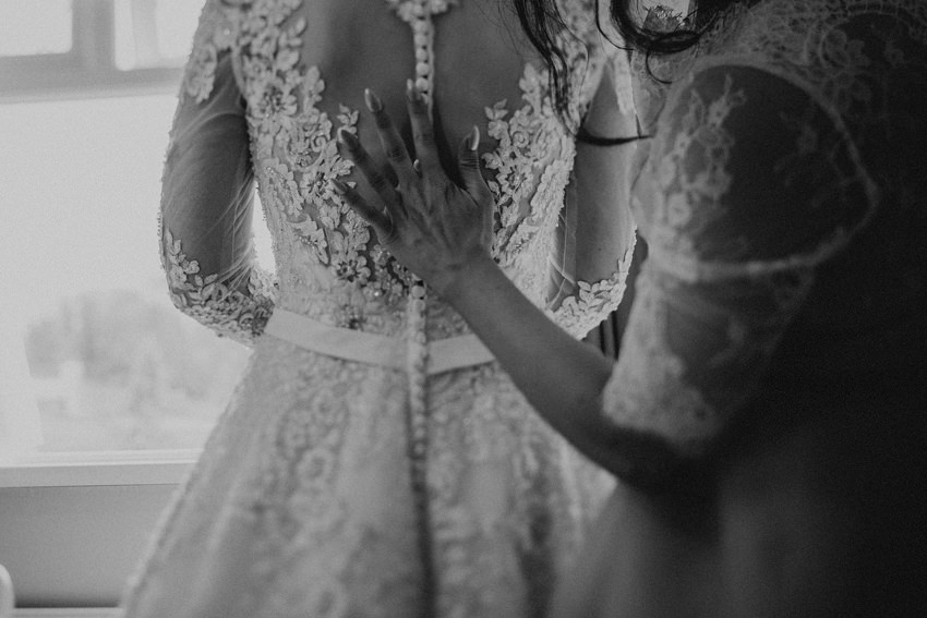 sister of the bride is checking all the buttons on the back of the dress