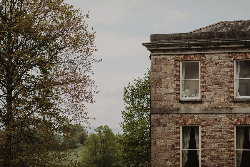 bride in the window at the makeup - documentary photographer in tipperary