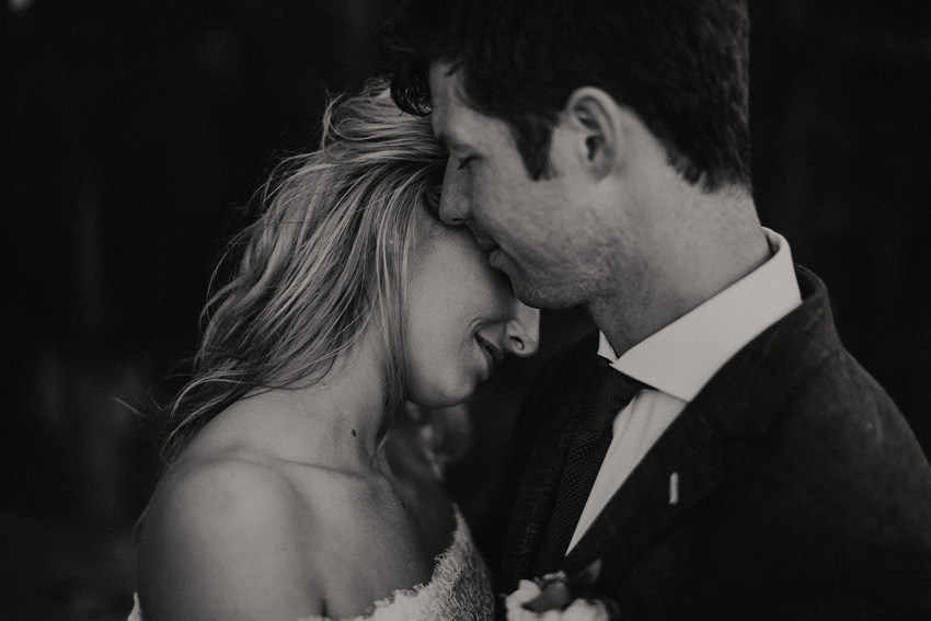 black and white photo groom is touching brides cheek with his lips